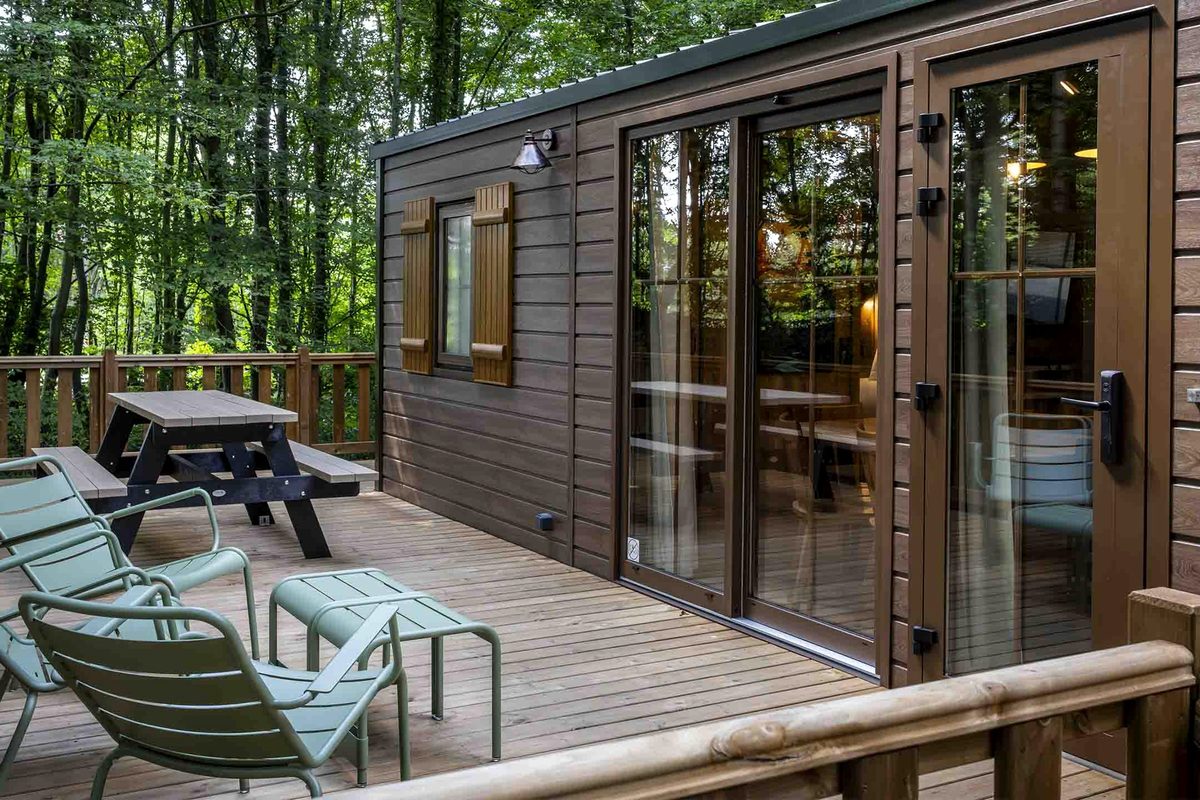 A timber cabin at Disney Davy Crockett Ranch, its decked terrace set with chairs and a picnic table among the trees