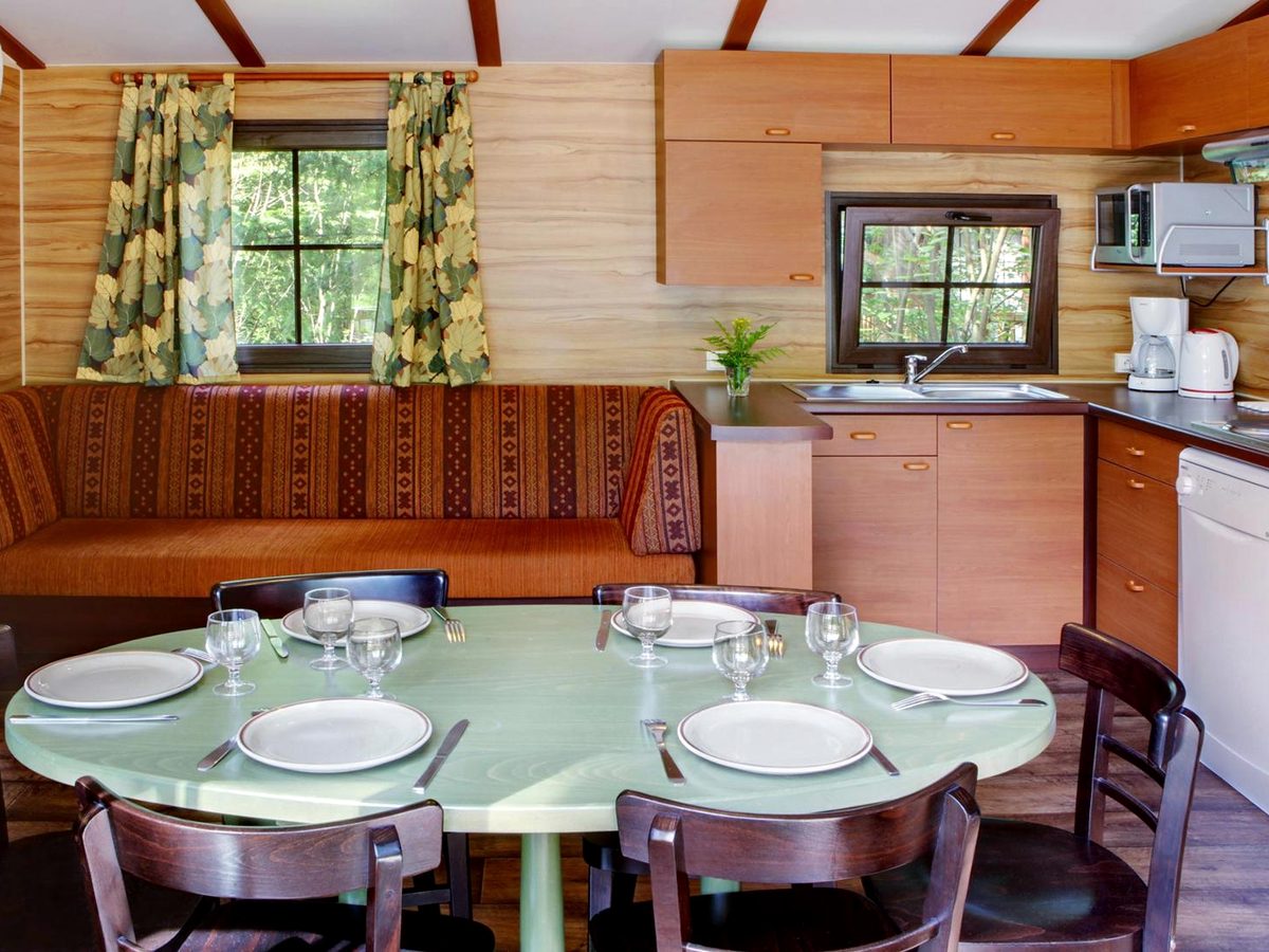 The dining table inside a Davy Crockett Ranch cabin, laid with plates and glasses beside the kitchen units and sofa