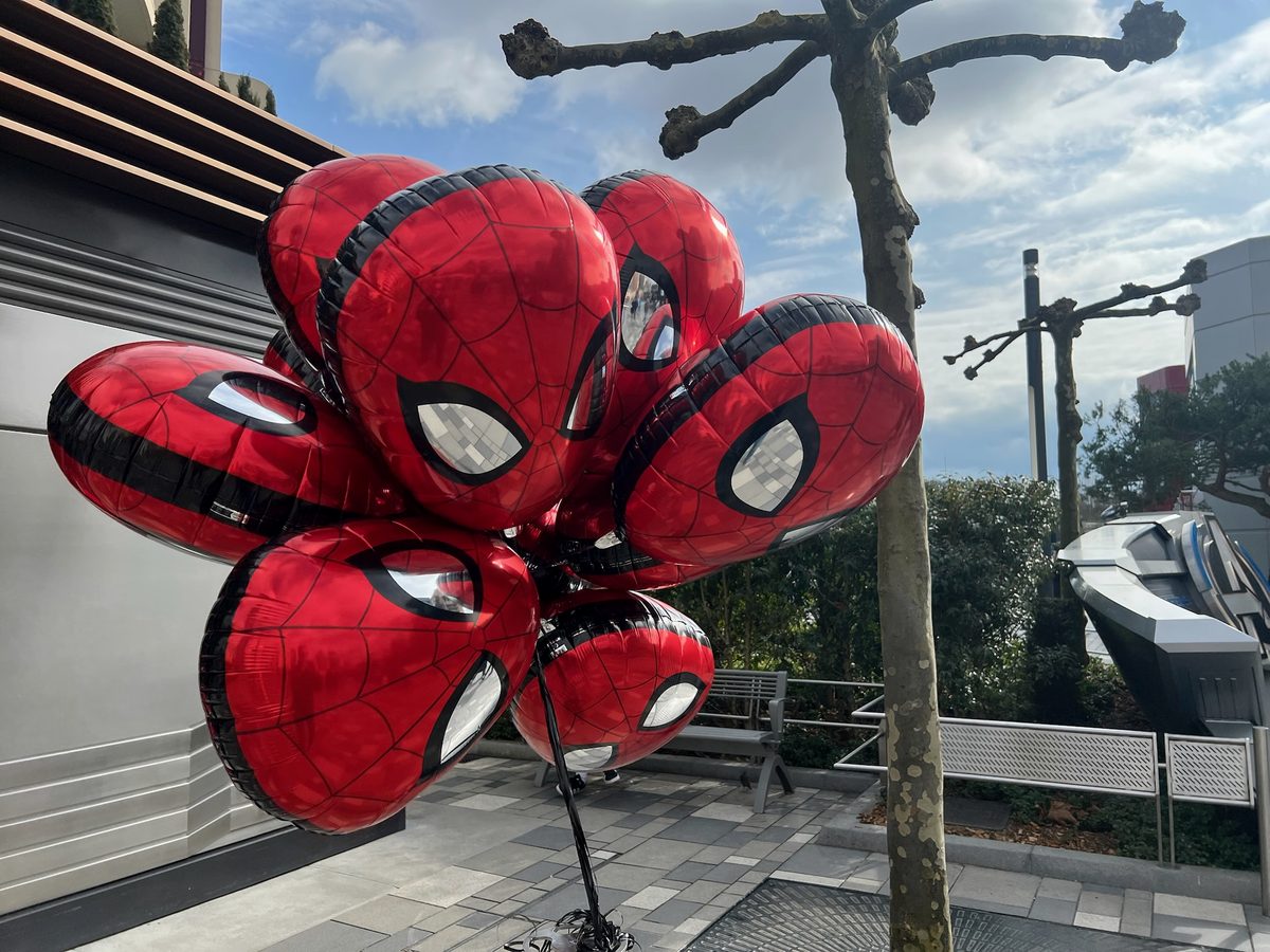 A bunch of Spider-Man balloons against a plane tree and blue sky in Avengers Campus
