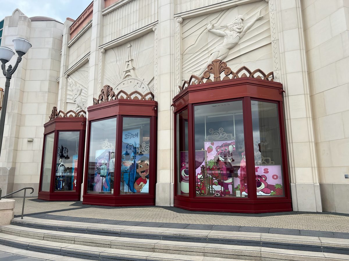 Three bay shop windows on a pale stone Art Deco facade, dressed with Disney character displays including Stitch and Lotso