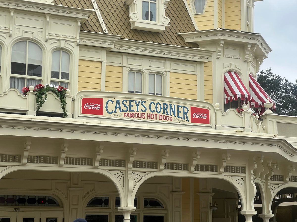 The yellow Victorian building and Casey's Corner sign with its striped awnings on Main Street, U.S.A.