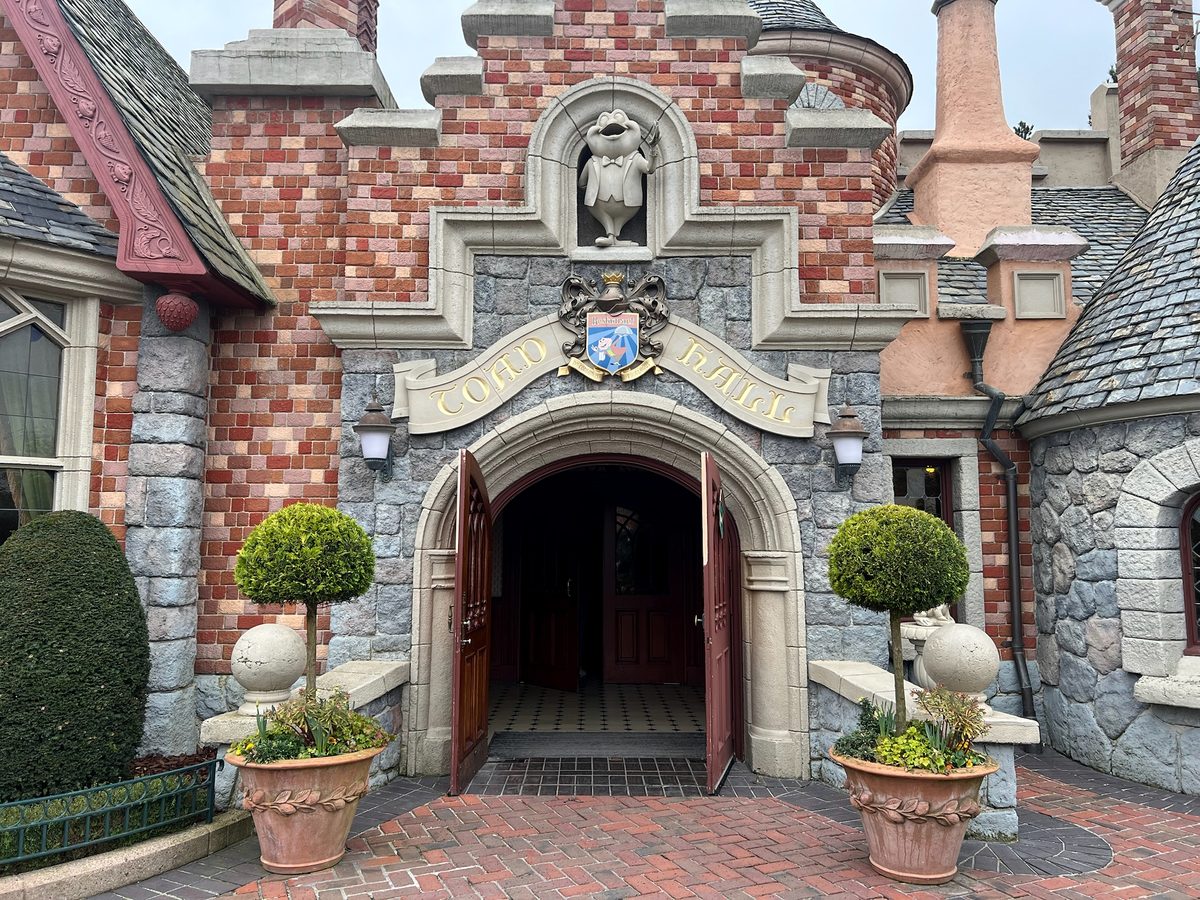 The stone and brick entrance of Toad Hall, Mr Toad's statue set above the door