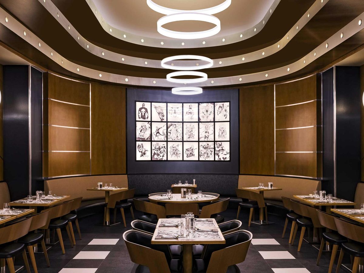 The Downtown Restaurant dining room, art-deco seating and a chequered floor with a backlit wall of black-and-white comic art