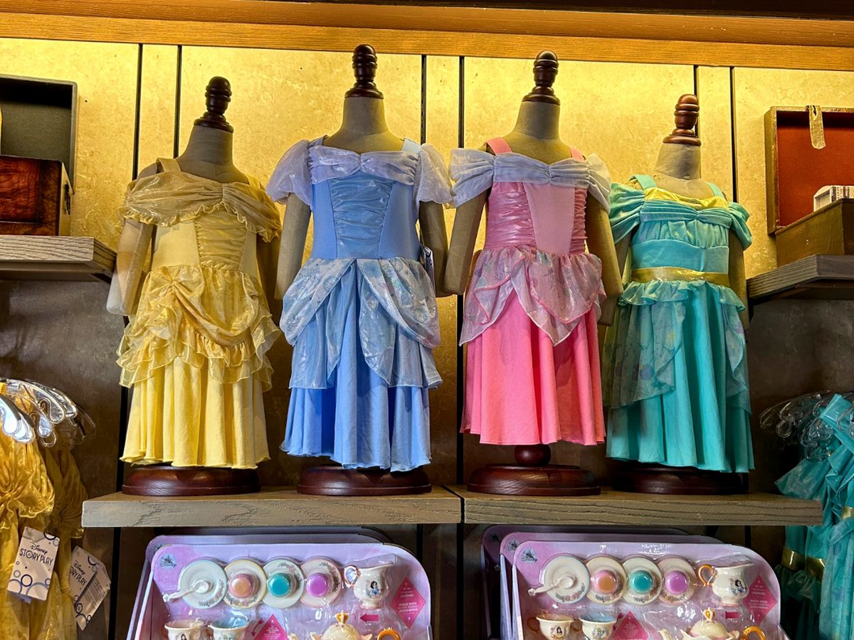 Princess costume dresses in yellow, blue, pink and green displayed on child-size mannequins inside Bibbidi Bobbidi Boutique at Magic Kingdom