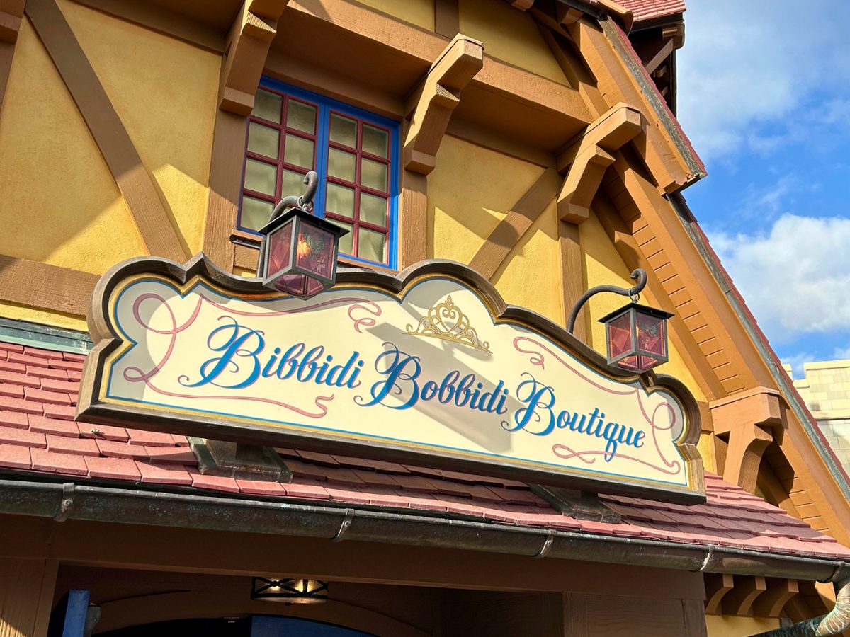 The painted sign for Bibbidi Bobbidi Boutique with a tiara motif, on the Tudor-style shopfront by Cinderella Castle at Magic Kingdom