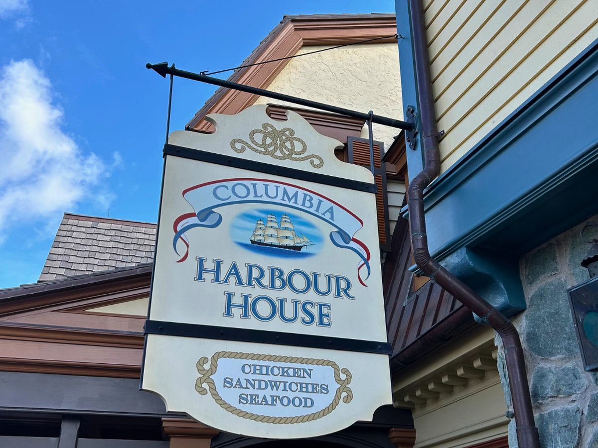 The hanging nautical sign for Columbia Harbour House in Liberty Square at Magic Kingdom, reading chicken, sandwiches and seafood beneath a sailing ship