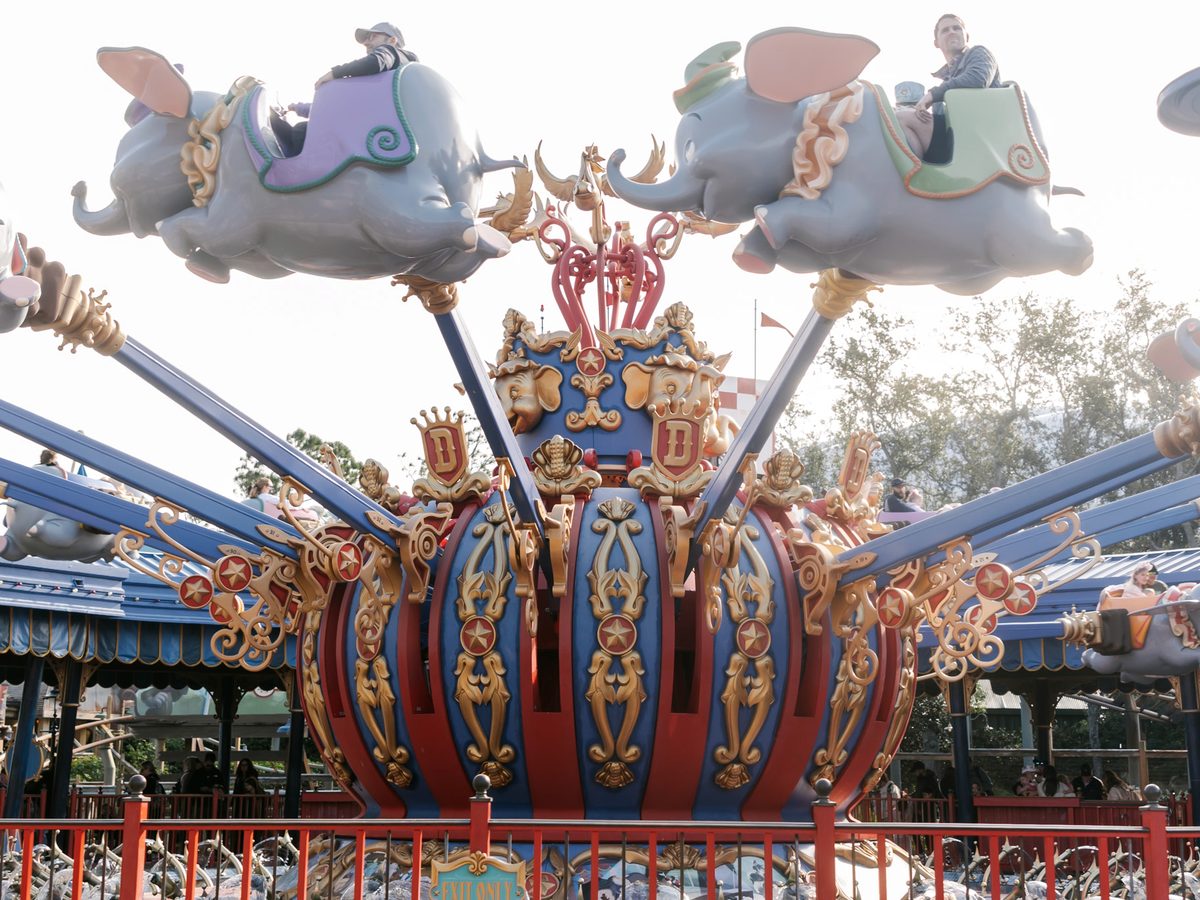 Dumbo the Flying Elephant ride vehicles in the air mid-ride at Magic Kingdom, families flying the elephants around the gold crown centrepiece