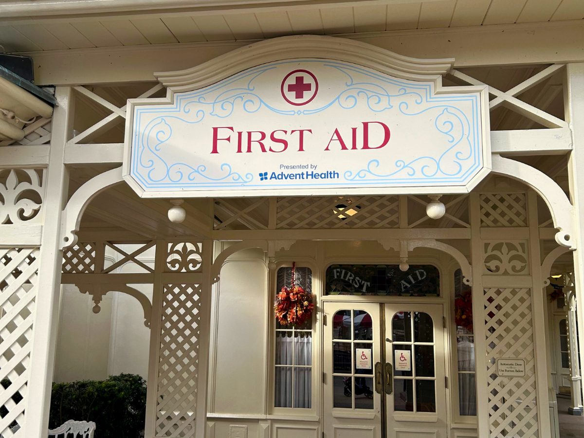 The matching cream porch and First Aid sign at Magic Kingdom, sharing a courtyard with the Baby Care Center, autumn wreaths on its doors