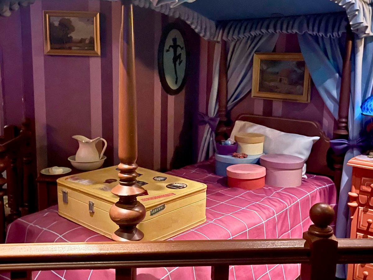 The nursery scene in the Peter Pan's Flight queue at Magic Kingdom, a four-poster bed with hat boxes and a suitcase and Peter Pan's shadow on the wall