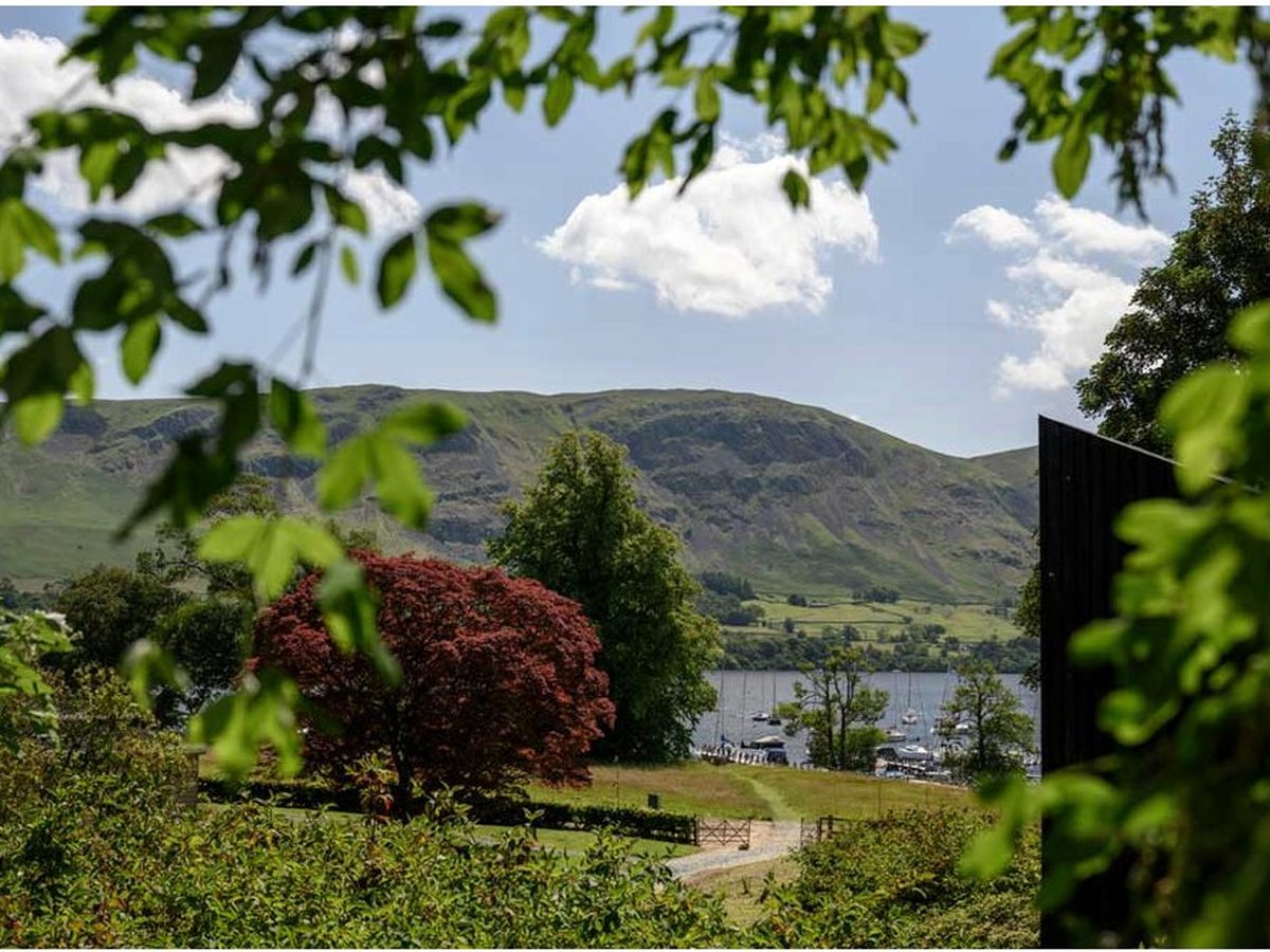 A view framed by trees and a red-leaved acer down over the lake to distant fells.
