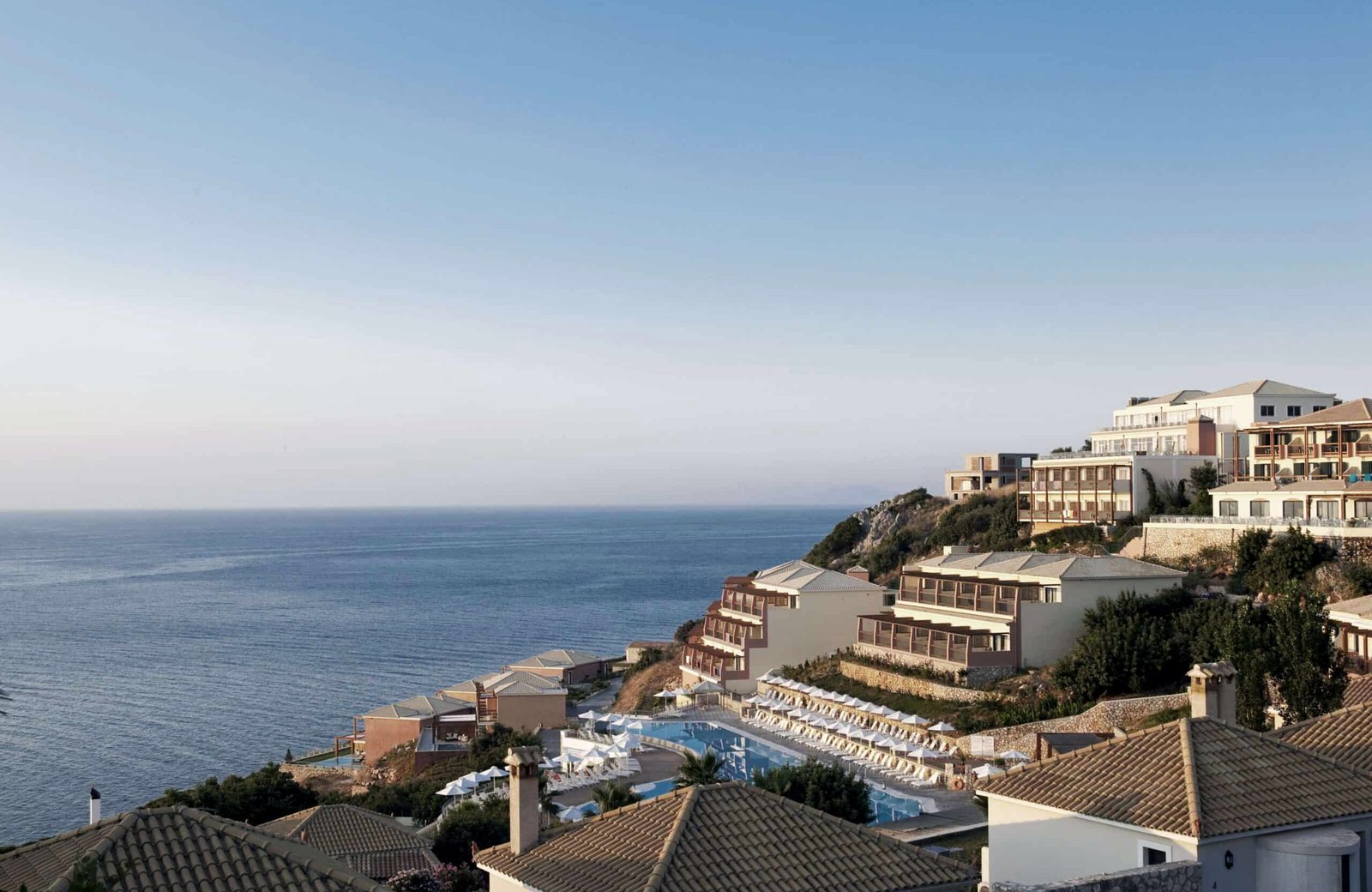 Apostolata Island Resort on a hillside above the Ionian Sea, with the main pool and terrace looking out to the water.