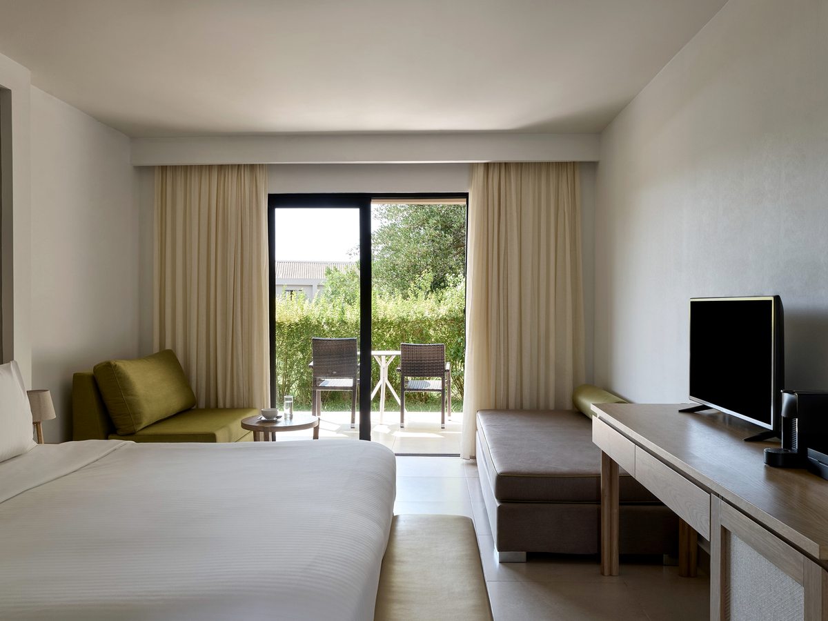 Room with a double bed, a green day sofa, a wall-mounted TV and glass doors to a furnished garden terrace.