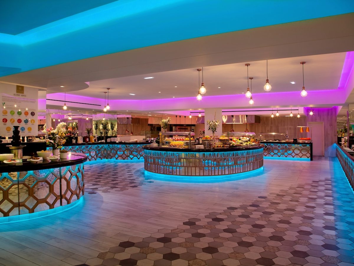 Curved buffet counters and serving islands under coloured lighting in the main buffet restaurant.