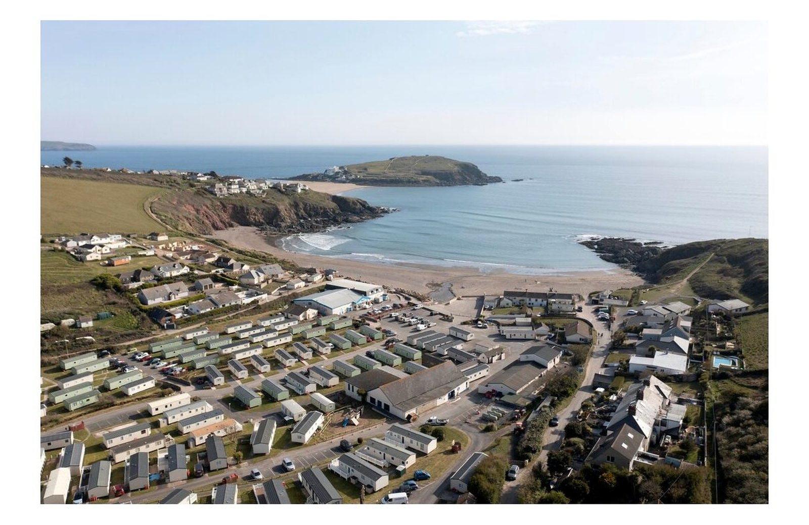Challaborough Bay Holiday Park: static caravans and lodges set on the slopes of a sheltered South Devon cove, with a sandy Blue Flag beach below and Burgh Island out in the bay.