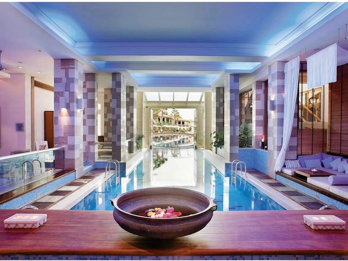 An indoor pool running between stone-tiled columns towards a glazed far wall that opens to the gardens.