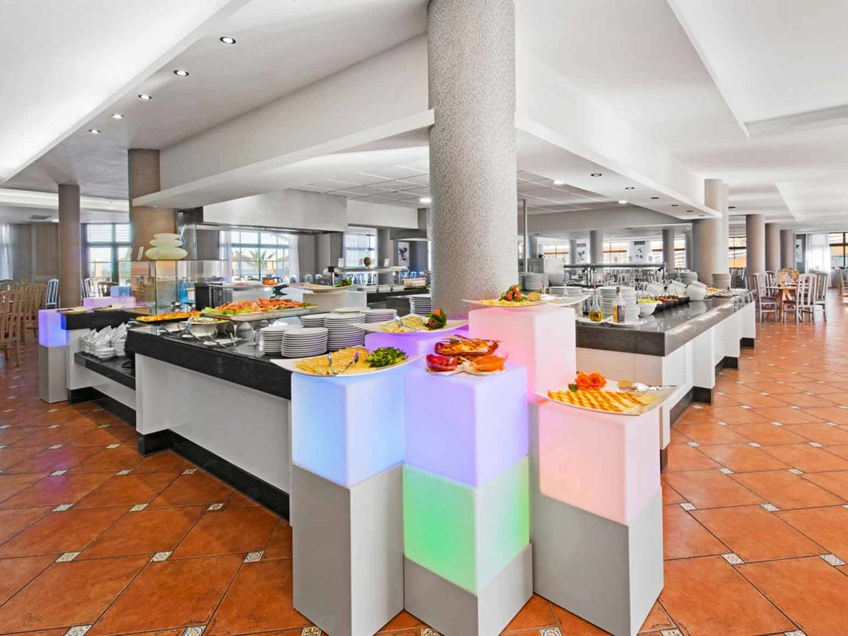 The buffet restaurant with illuminated serving islands, food displays and dining tables with white chairs.