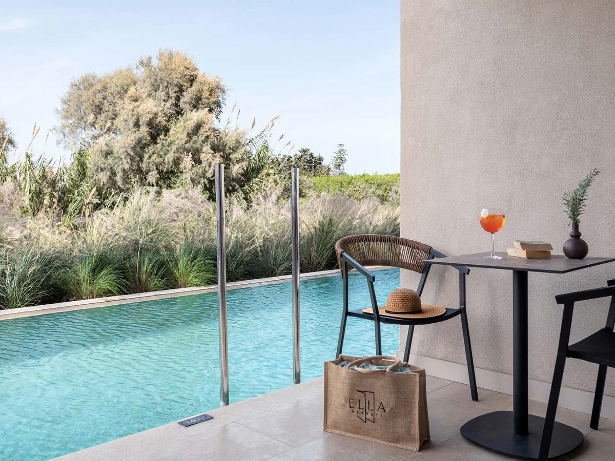 A small pool beside a room's private terrace with a table, chairs and a pool ladder