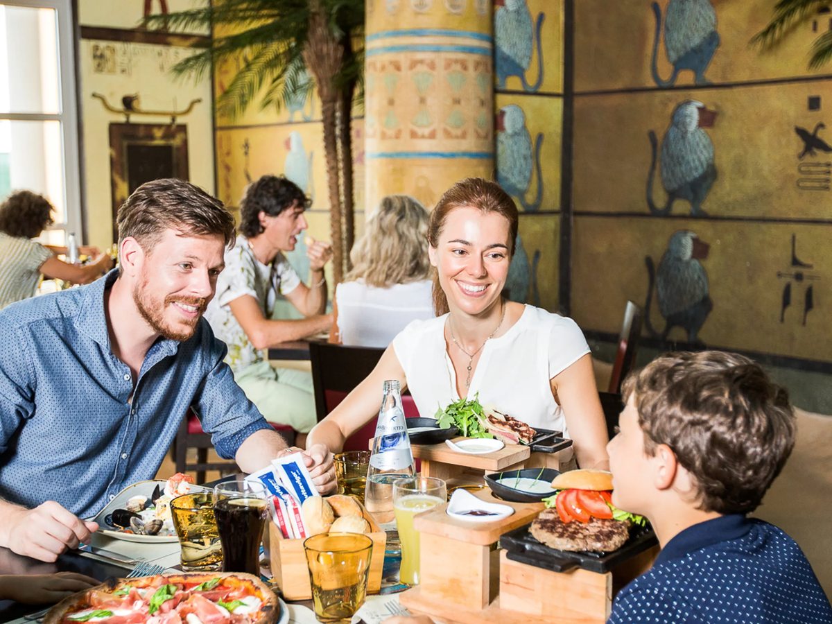 A family eating at a table in the Tutankhamon restaurant, among painted Egyptian columns and hieroglyph murals.