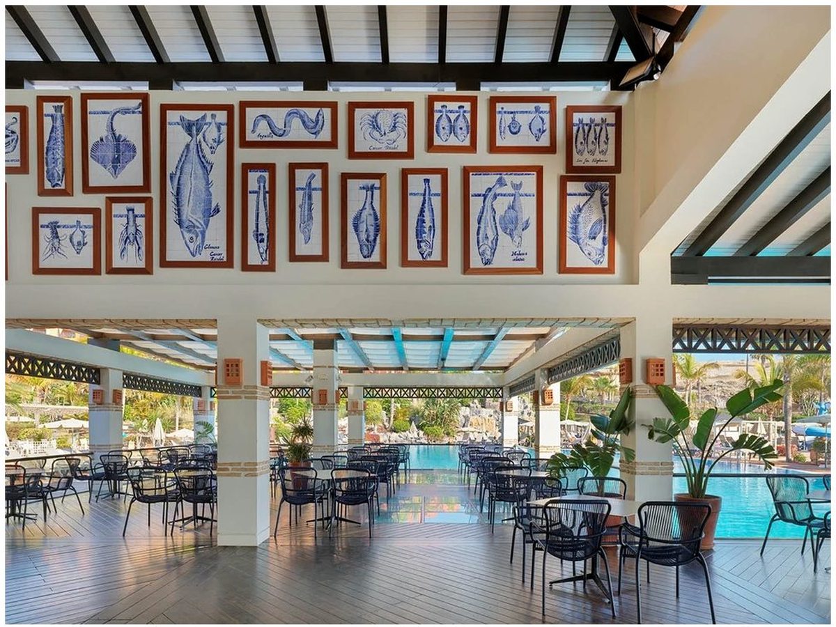 A covered poolside bar with white columns and blue-and-white tiled fish panels, tables and chairs looking out to the pool.
