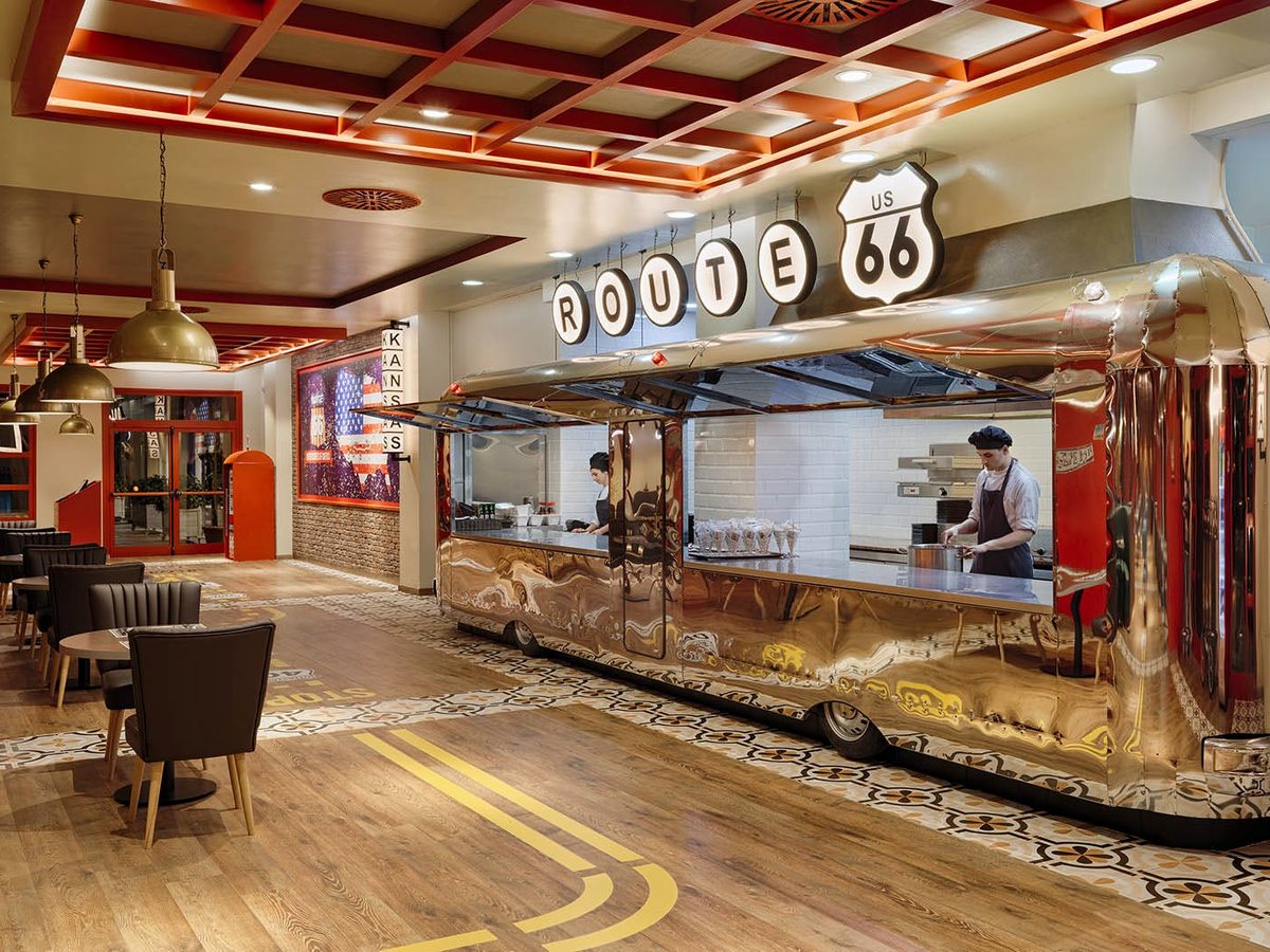 American diner-styled restaurant with a chrome counter, a road-marking floor and a Route 66 sign above the open kitchen.