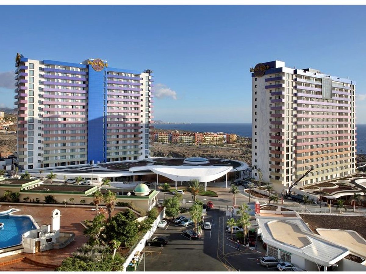 Aerial view of the resort's two high-rise towers on the seafront, the pools and grounds below them and the coast beyond.