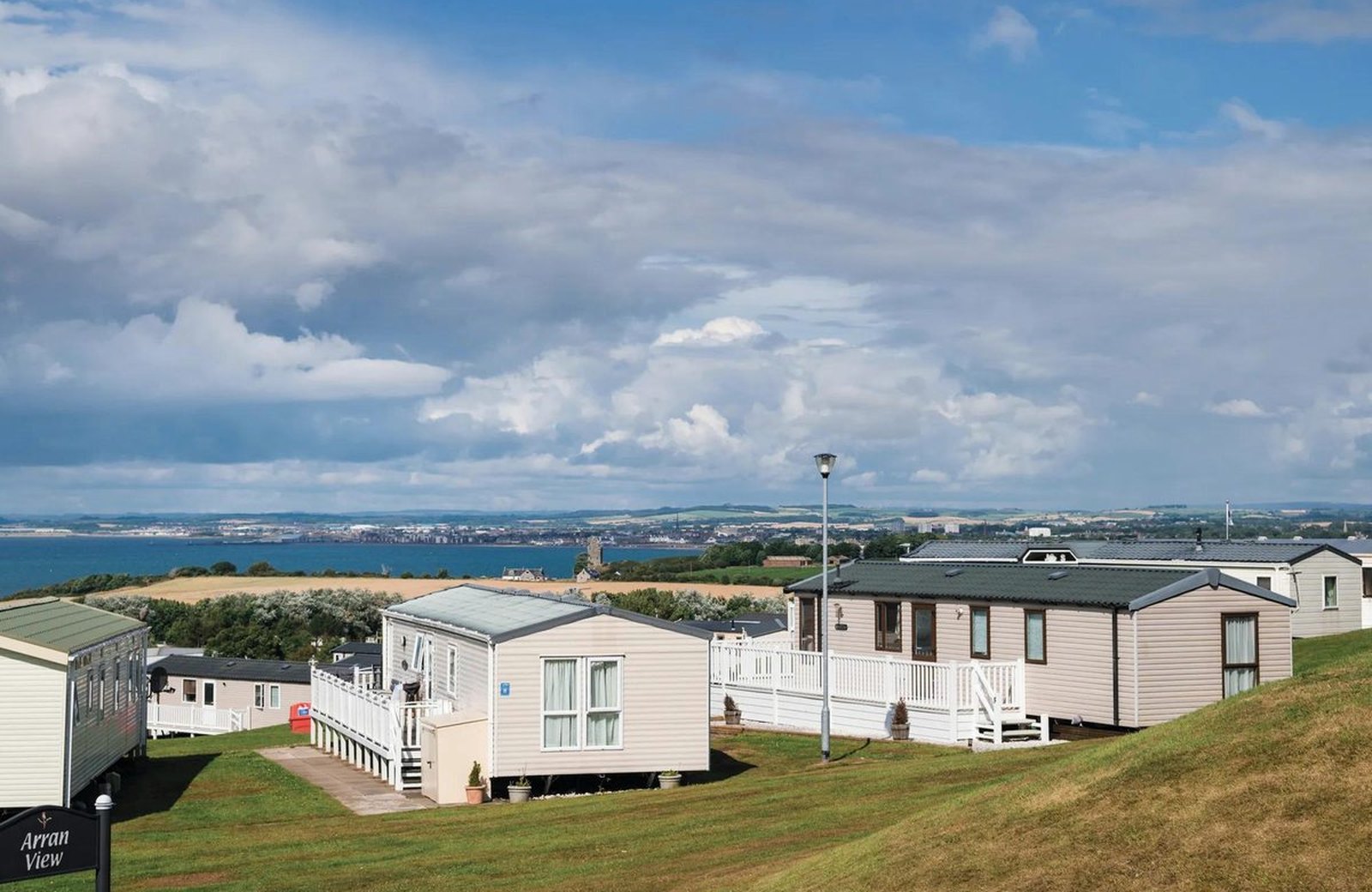 Haven Craig Tara: rows of static caravans set across a green hillside above the Ayrshire coast, with the Firth of Clyde and the hills of the Isle of Arran beyond.