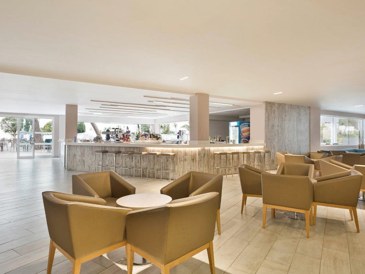 An indoor lounge bar with tub chairs around low round tables.