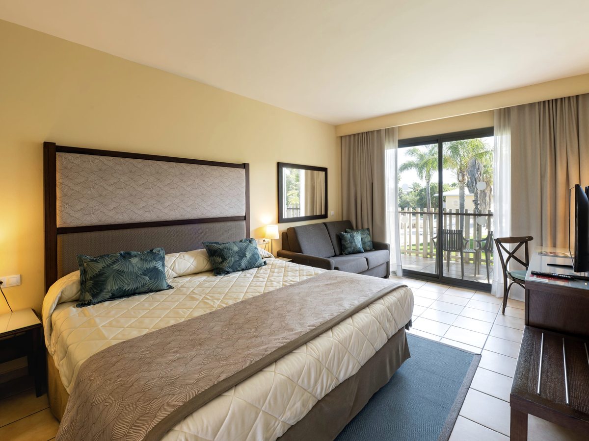 A Standard Room with a large double bed, a sofa and sliding doors onto a balcony over the gardens.