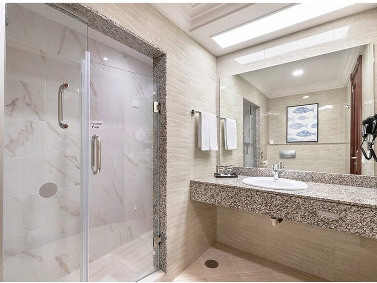 Room bathroom with a glass walk-in shower, a granite vanity with a single sink and a large mirror.