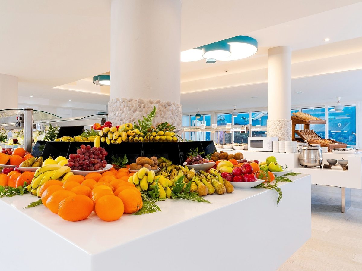 A central buffet island piled with fresh oranges, bananas and other fruit.