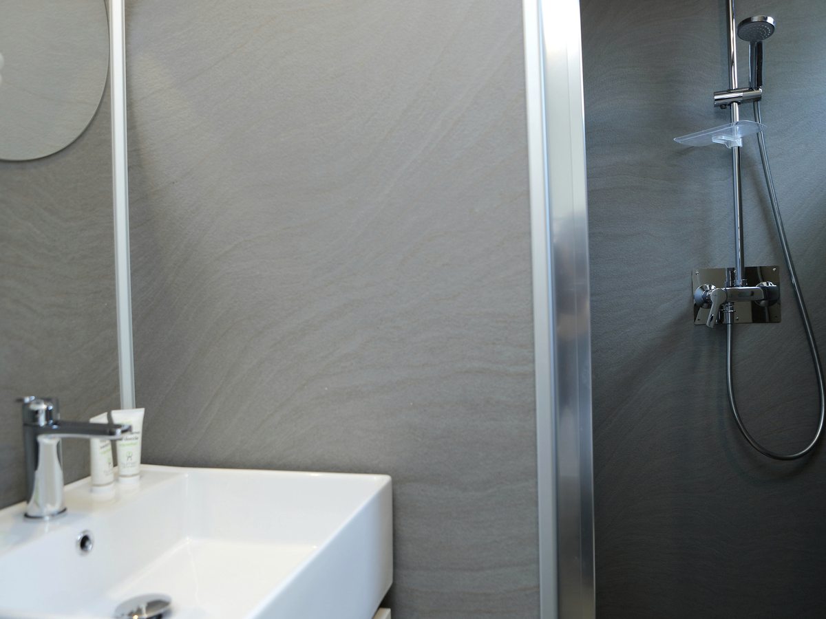 A white bathroom with a glass shower cubicle and a rainfall shower head.