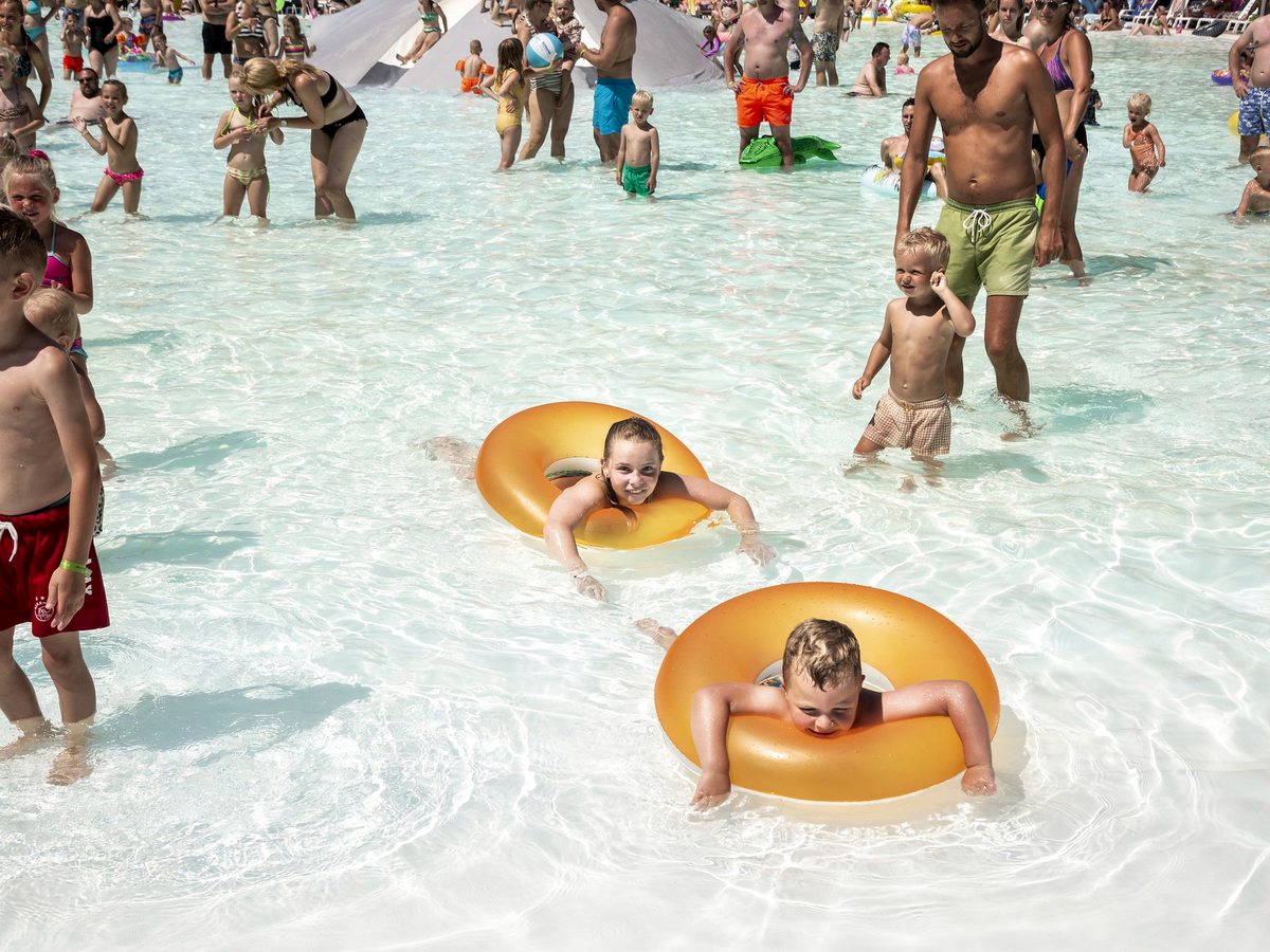 Toddlers sitting and playing with rubber rings in a very shallow pool.