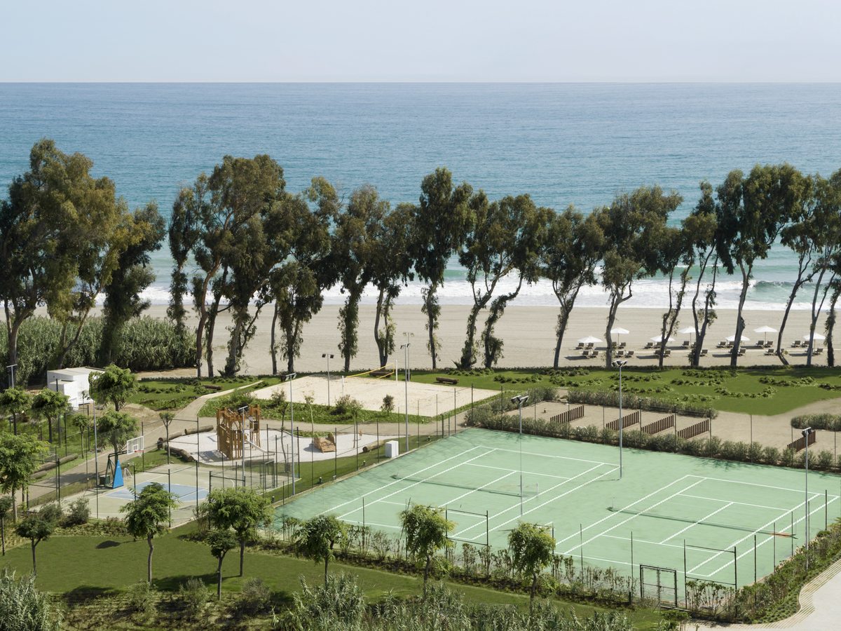 The sports centre at Ikos Andalusia, tennis courts, a basketball court, a beach volleyball court and a playground on level ground between the gardens and the beach.