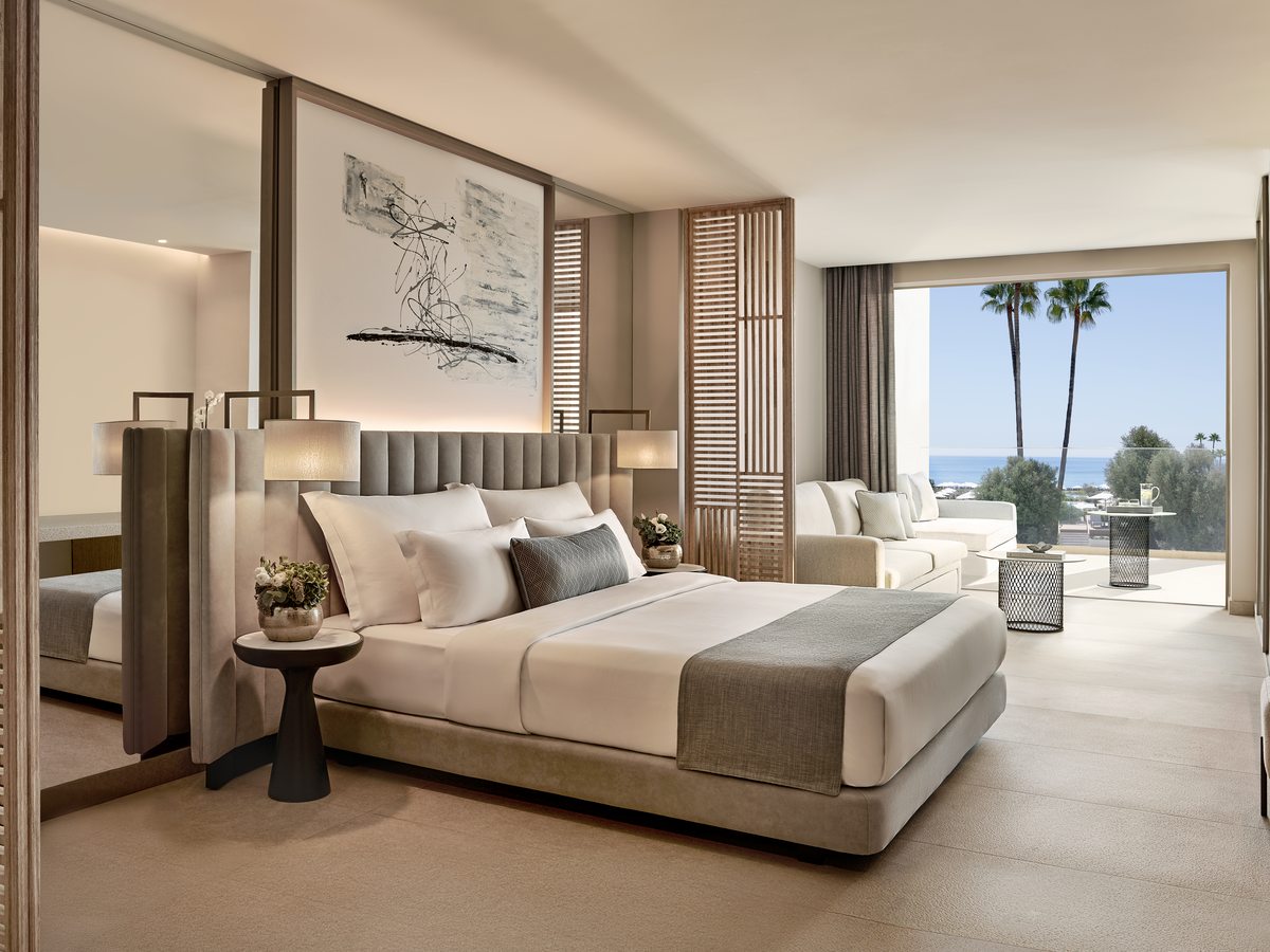 A Junior Suite at Ikos Andalusia, an open-plan room with a bed and seating and the sea through the balcony doors.