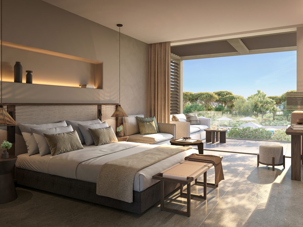 A Family Room at Ikos Kissamos, with a king bed, armchairs and a table by glass doors opening onto a terrace.
