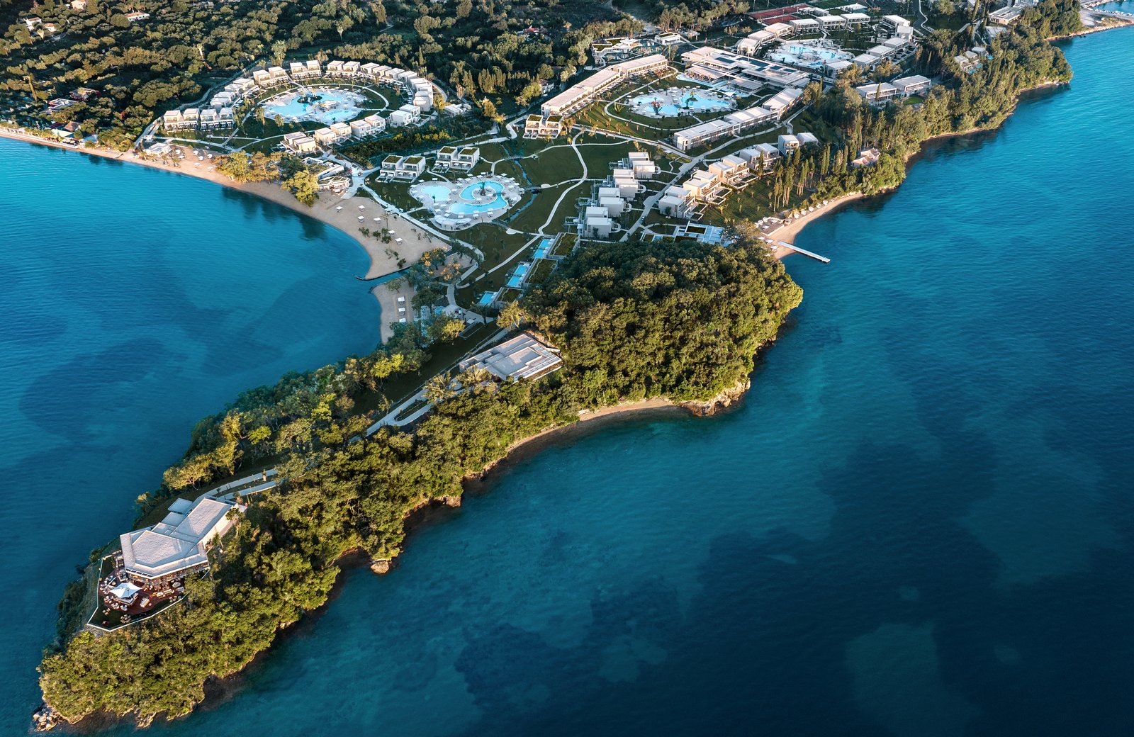 Ikos Odisia from the air: a low-rise resort on a green Corfu peninsula ringed by turquoise sea.