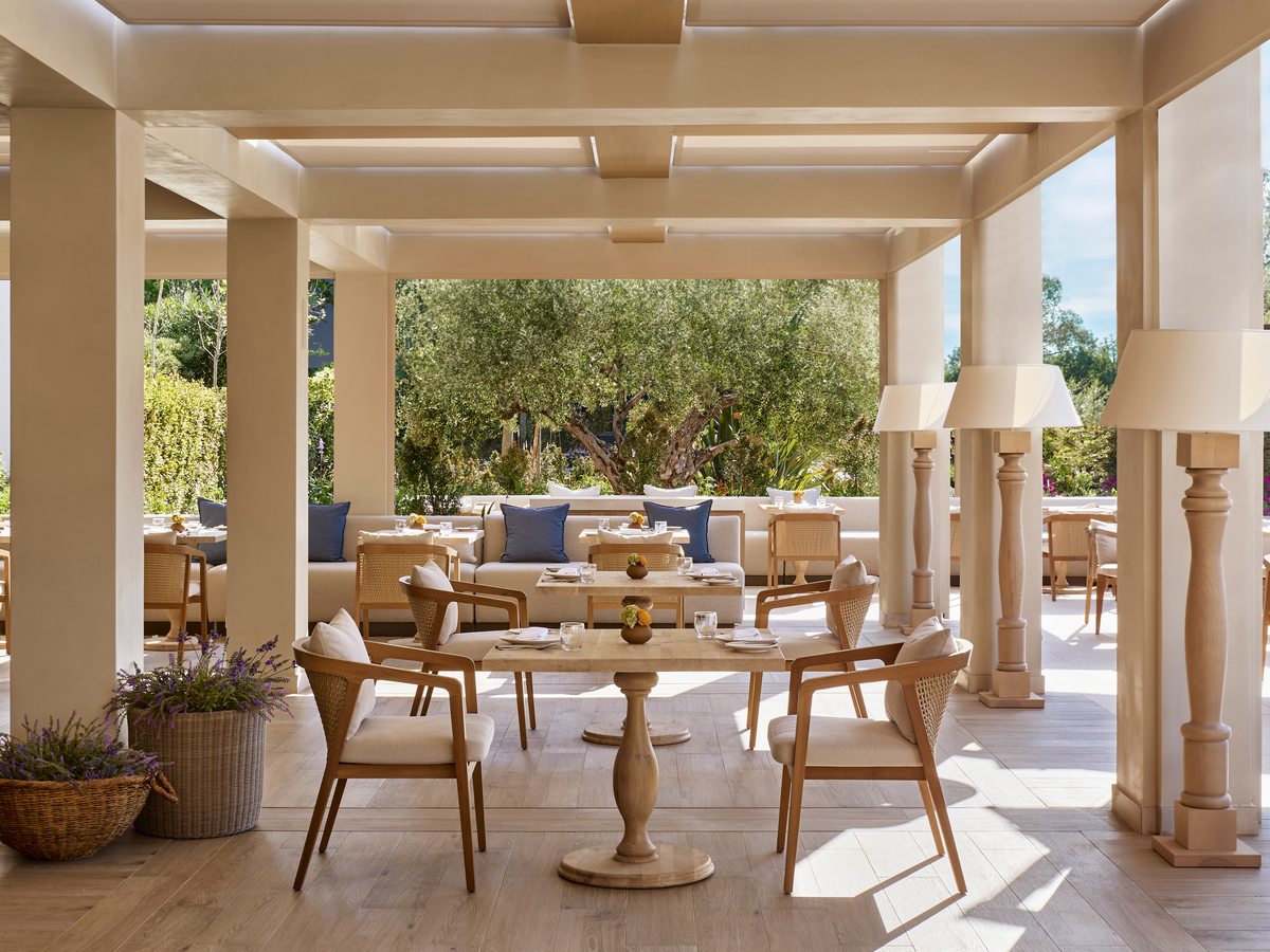 The covered terrace at Provence, with pale stone columns, wooden chairs and round tables.