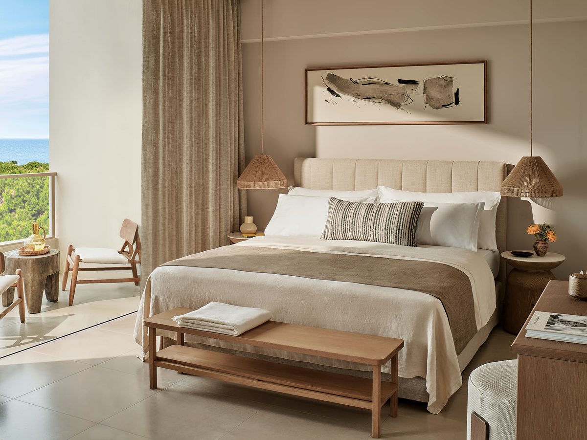 A Panorama Junior Suite with a double bed, a bench at its foot and a seating area by the terrace doors.