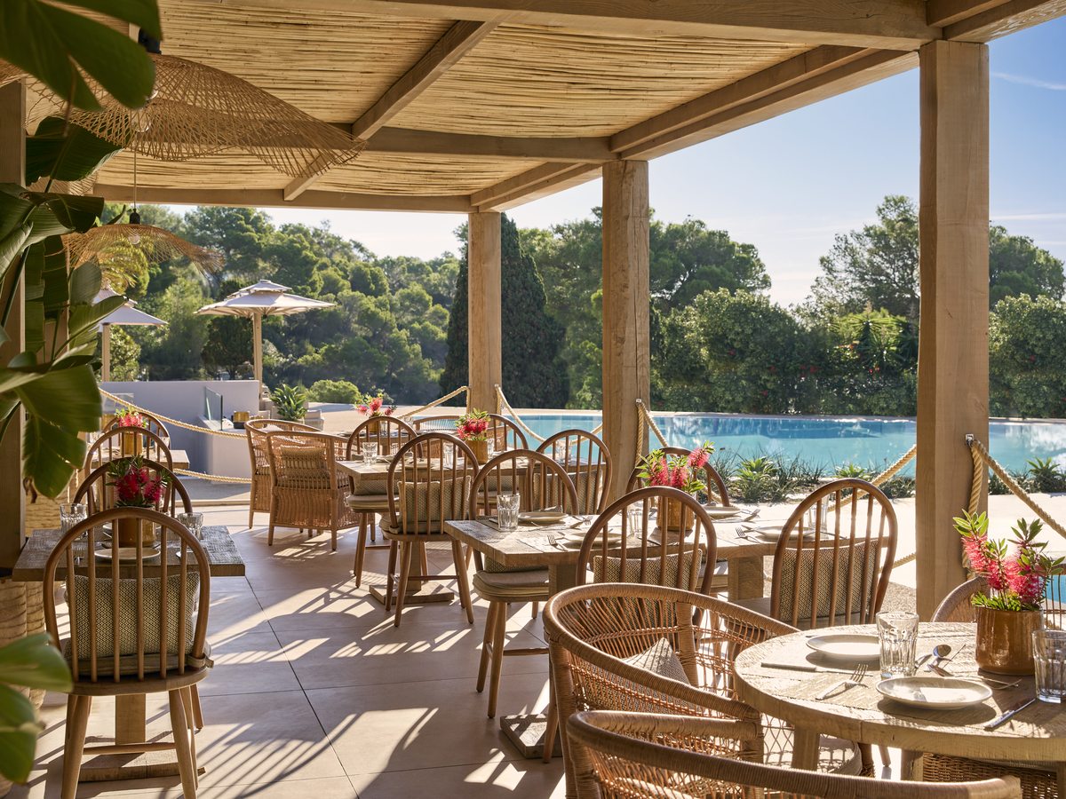 The covered terrace at the Beach Club restaurant, cane chairs around set tables beside the pool.