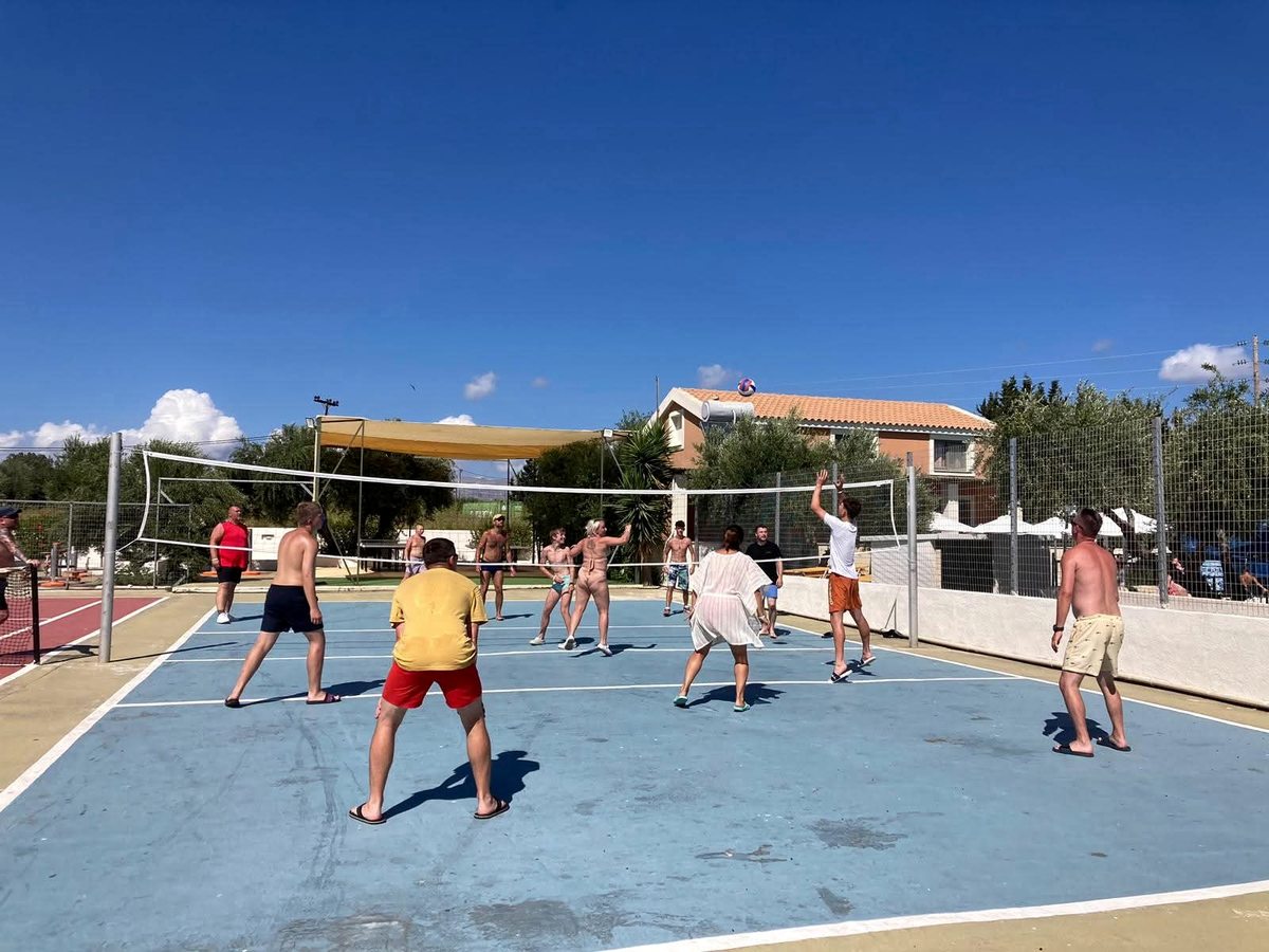A group of guests playing a ball game together on the resort's outdoor court in bright sun.