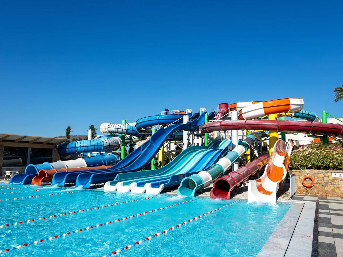 A row of coloured tube and open water slides ending in a large pool marked with lane ropes.