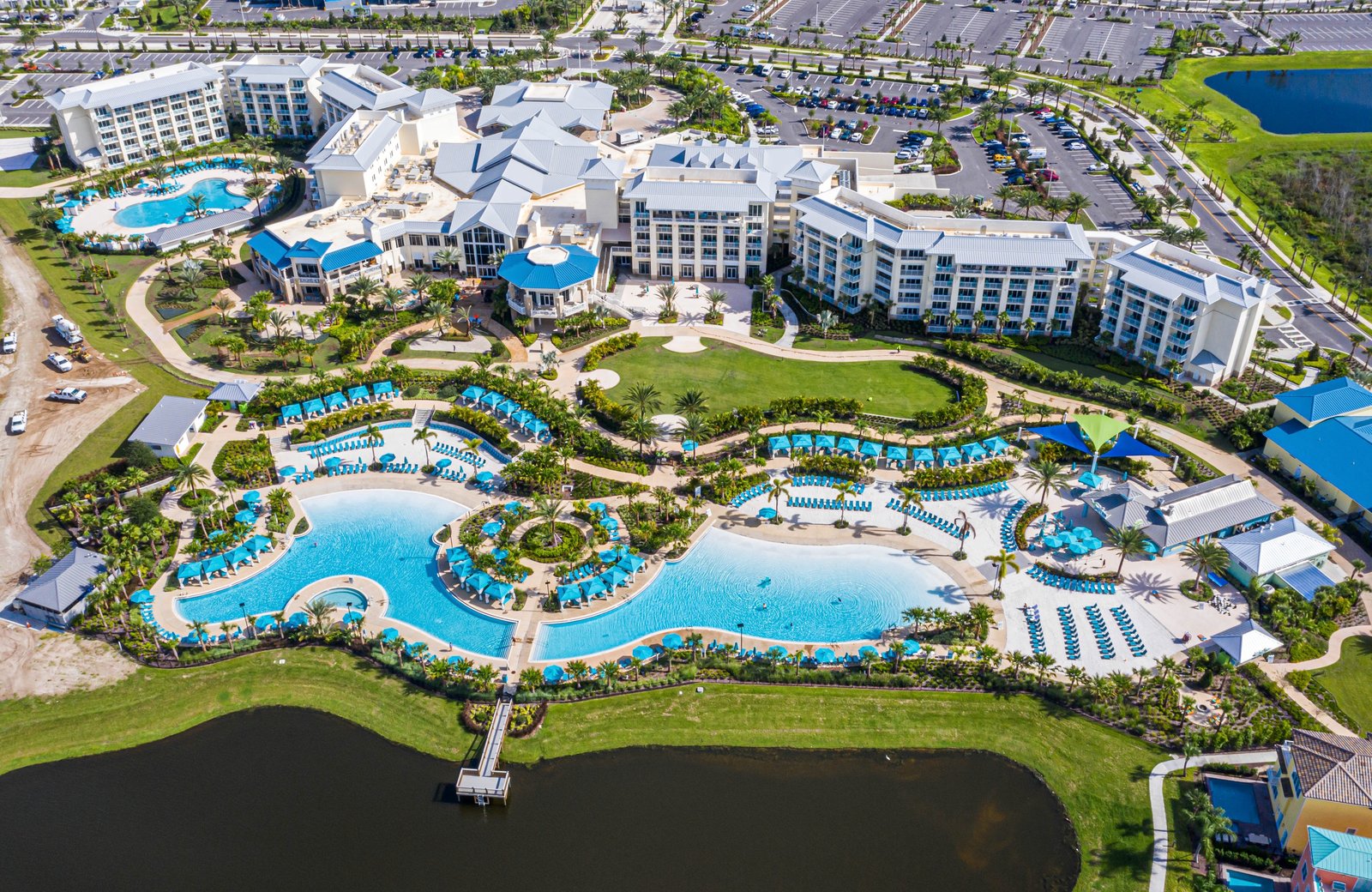 Margaritaville Resort Orlando from the air: a large resort built around freeform turquoise lagoon pools and a lake, with pastel cottage neighbourhoods and the hotel spread around them.