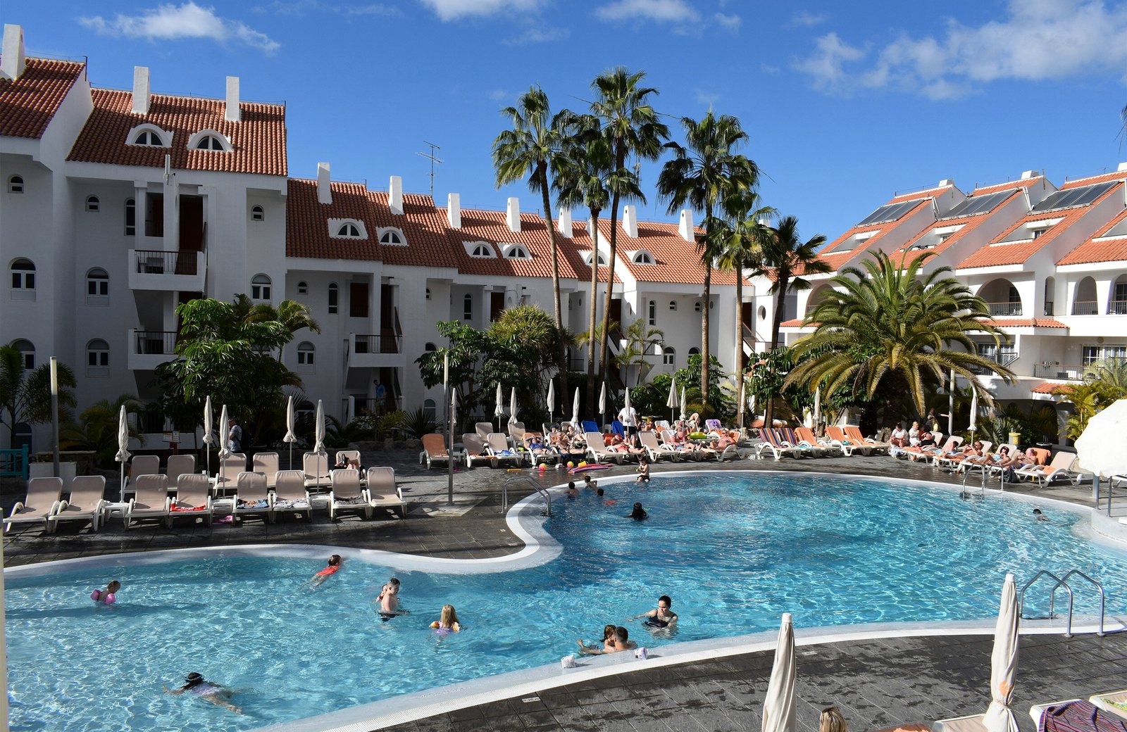 The main pool at Paradise Park Fun Lifestyle, with families in the water, rows of sun loungers and the hotel's white blocks and palms behind.