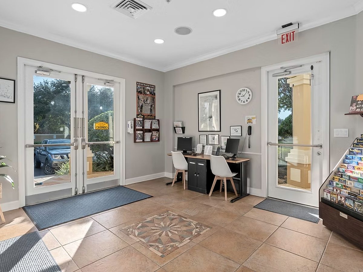 A reception room with two desks, office chairs, wall-mounted brochure racks and glazed doors leading to a patio.